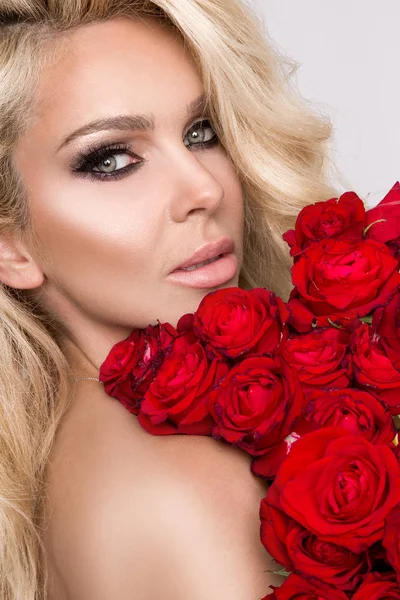 Güzel seksi sarışın beyaz bir arka plan üzerinde zarif iç çamaşırı. Bir buket kırmızı gül tutan kız.