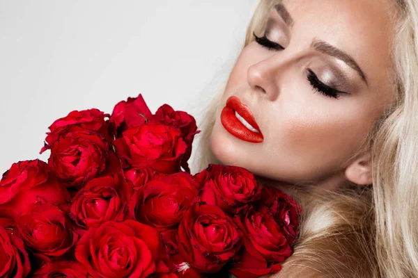 白い背景にエレガントなランジェリーでセクシーなブロンドの美しい。赤いバラの花束を持って女の子. — ストック写真