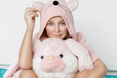 Sevimli küçük kız tavşan kulakları ile pembe bir Paskalya tavşan maskot tutan bir Kazak giymiş