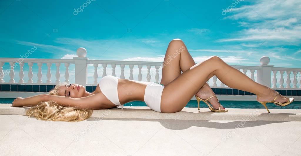 Stunning, sexy blonde female model  with perfect body wearing a bikini, elegant swimsuit on amazing view with palm trees sea in Cannes,  Santorini