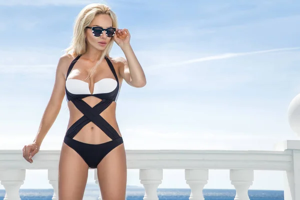 Vackra fantastisk sexig blond kvinna i solglasögon och eleganta kläder och bikini vid poolen med fantastisk utsikt över havet och ön Santorini — Stockfoto