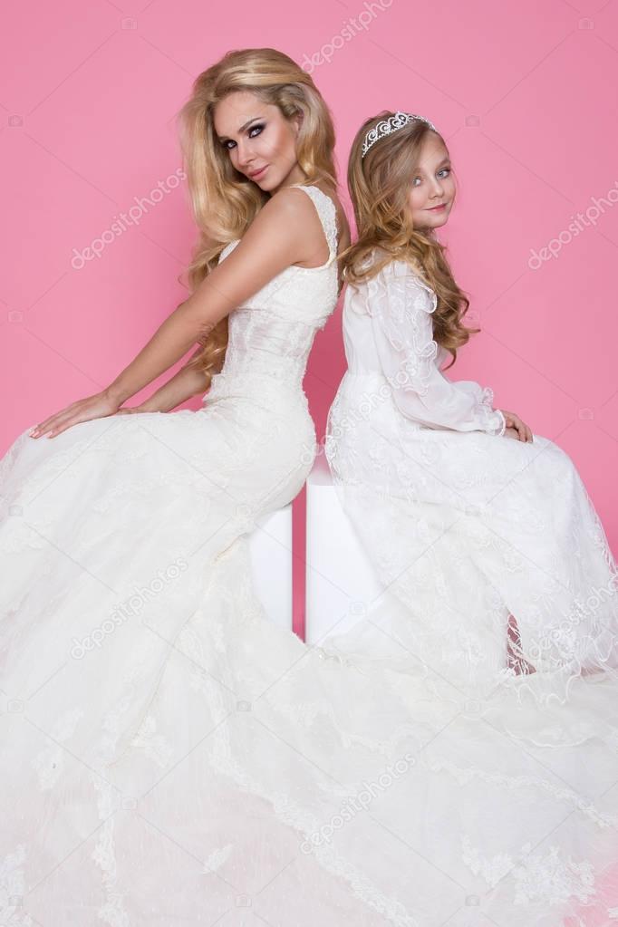 Beautiful blonde female model, mother with blonde daughter in dresses. They have beautiful wedding dresses