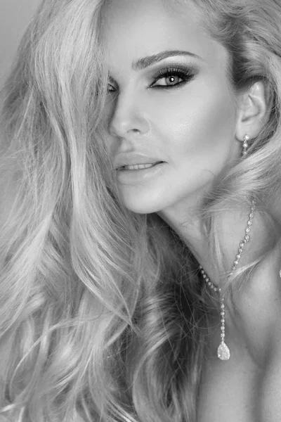 Güzel genç, seksi sarışın kadın portre, bir prenses kıvırcık uzun saç modeli ile uzun bir tren, inci ve dantel pembe arka plan şehvetli görünüyor beyaz uzun şaşırtıcı gelinlik gelin