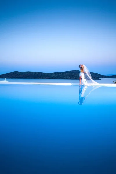 Belle mannequin blonde féminine avec un corps parfait et des cheveux longs étonnants sur l'île de Santorin en Grèce et autour d'elle est une vue incroyable — Photo