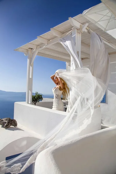 Hermosa modelo rubia femenina con un cuerpo perfecto y cabello largo increíble en la isla de Santorini en Grecia y alrededor de ella es increíble vista —  Fotos de Stock