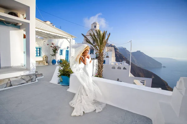 Hermosa modelo rubia femenina con un cuerpo perfecto y cabello largo increíble en la isla de Santorini en Grecia y alrededor de ella es increíble vista —  Fotos de Stock