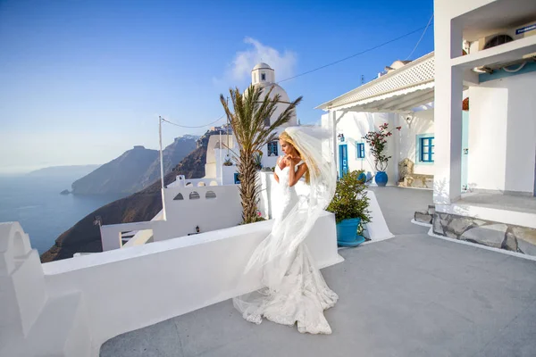 Hermosa modelo rubia femenina con un cuerpo perfecto y cabello largo increíble en la isla de Santorini en Grecia y alrededor de ella es increíble vista —  Fotos de Stock