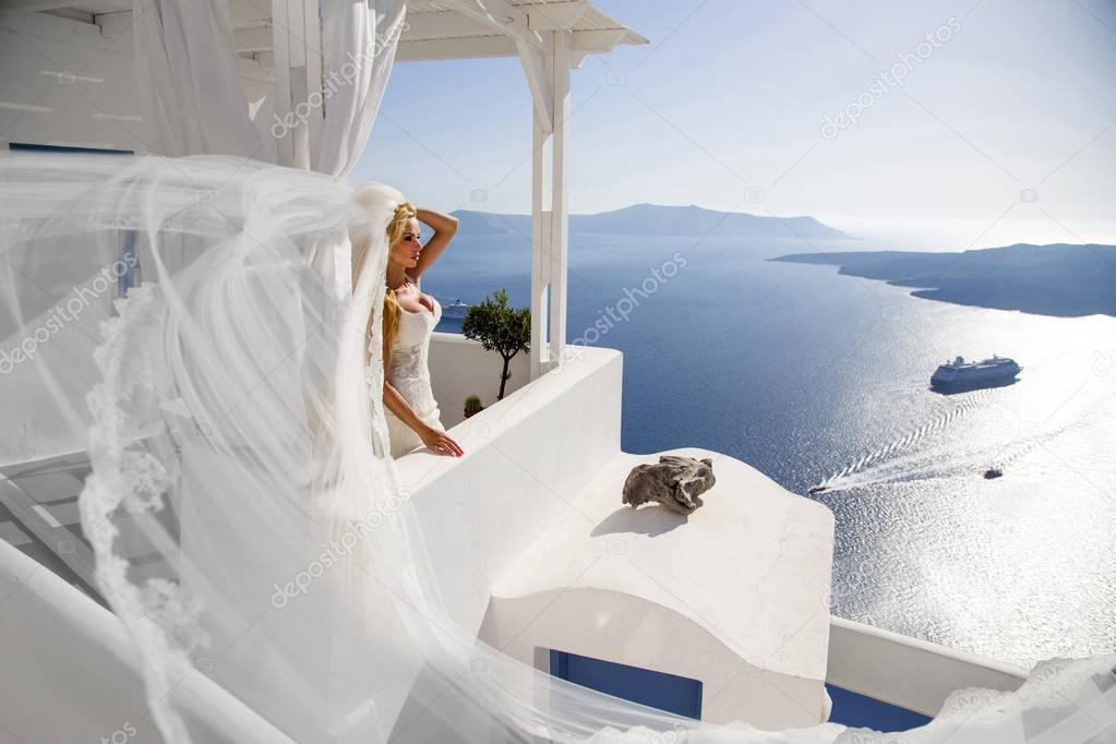 Beautiful female blonde model with  a perfect body and amazing long hair on the island of Santorini in Greece and around it is amazing view