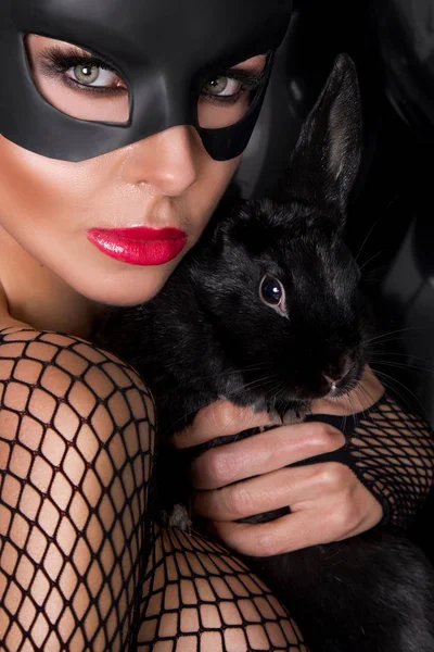 seksi güzel genç bir siyah karnaval maskesi, tavşan kulağı, geçinmek elele modelinde siyah balon Nick tavşan ve sensually bodystocking fileli giyen kamera bakar