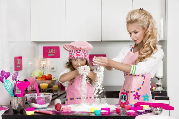 Beautiful stunning woman mother and daughter in aprons kitchen cooking in  the kitchen cookies and pasta noodles Stock Photo by ©marcink3333 169331726