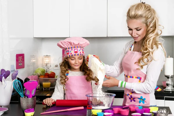 Beautiful stunning woman mother and daughter in aprons kitchen cooking in the kitchen cookies and pasta noodles