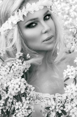 Bir buket bahar tutan bir Bahar elbise giyen bir ağaç salıncakta çarpıcı sarışın seksi doğal kadın salıncakta