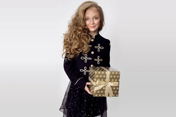 Stunning beautiful little girl with long blond hair holds in her hands gifts, joyfully look into the lens at Christmas time — Stock Photo, Image