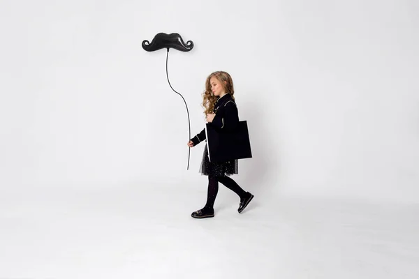 Elegante niña elegantemente vestida va de compras con una bolsa en el hombro y una mano sosteniendo un globo — Foto de Stock