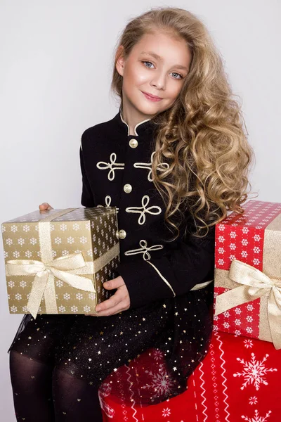 Menina bonita impressionante com longos cabelos loiros segura em suas mãos presentes, olhe alegremente para a lente no tempo de Natal — Fotografia de Stock