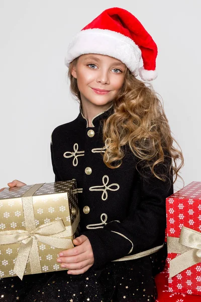 Εκπληκτικά όμορφο κοριτσάκι με μακριά ξανθά μαλλιά κατέχει τα δώρα της χέρια, χαρωπά κοιτάζετε μέσα στο φακό στο χρόνο Χριστουγέννων — Φωτογραφία Αρχείου