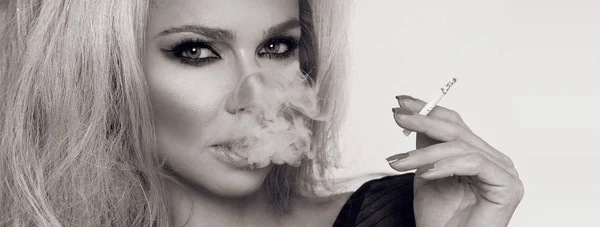 Sexy mujer rubia sensual femme fatale sentado en ropa interior erótica negro y fumar un cigarrillo — Foto de Stock