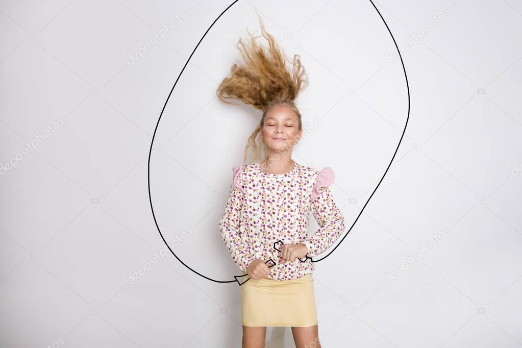 Pretty little girl with long blond hair jumping rope and joyfully smiles, is fun