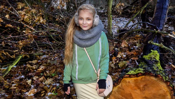 Hermosa niña dulce vestida con un abrigo de piel de oveja y botas sentadas en el tronco y en el fondo es la increíble vista del otoño y el invierno — Foto de Stock
