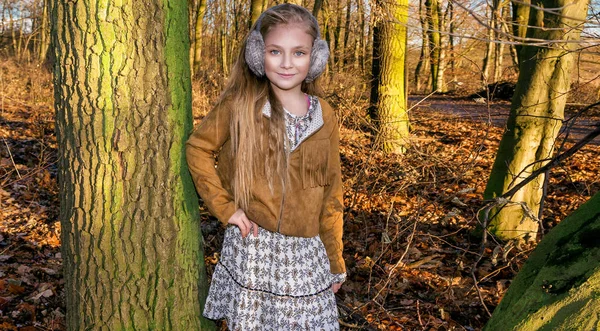 Hermosa niña dulce vestida con un abrigo de piel de oveja y botas sentadas en el tronco y en el fondo es la increíble vista del otoño y el invierno — Foto de Stock