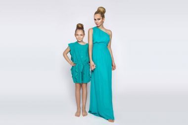 Beyaz bir arka plan üzerinde oturan sevimli sarışın kızı olan genç bir anne güzellik çarpıcı bir bahar kılığına girmiş