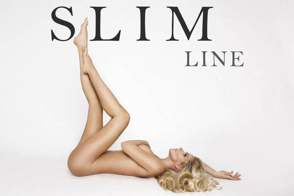 Beautiful, shapely female model with long blond hair, lies naked on a white background and covers the bust