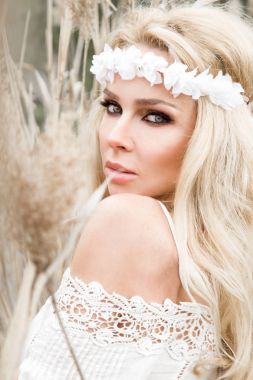 Bir buket bahar tutan bir Bahar elbise giyen bir ağaç salıncakta çarpıcı sarışın seksi doğal kadın salıncakta