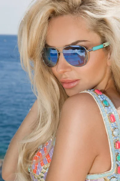 Hermosa mujer rubia sexy impresionante en gafas de sol y ropa elegante y bikini alrededor de la piscina con increíbles vistas al mar y la isla de Santorini —  Fotos de Stock