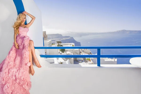 Mooie bruid blonde vrouwelijke model in fantastische trouwjurk vormt op het eiland Santorini in Griekenland en verder is het een prachtig uitzicht — Stockfoto