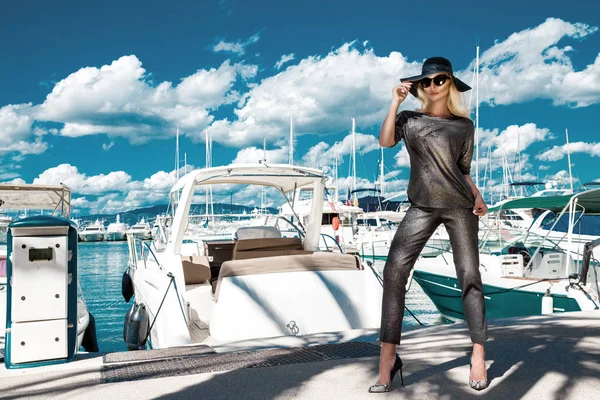 Vacker blond kvinna, stående i en elegant jacka och solglasögon vid havet med vacker utsikt — Stockfoto