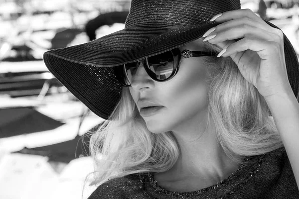 Белый портрет красивой черной элегантной и сексуальной блондинки в шляпе и солнцезащитных очках, которая стоит на яхте в Каннах, Франция — стоковое фото