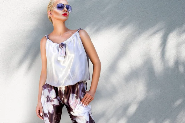 Şık bir kıyafet ve yüksek topuklu ayakkabılar ve güneş gözlüğü standları palmiye ağaçları ile Fransa'nın Cannes şaşırtıcı görünümünde giyen güzel olağanüstü çarpıcı zarif lüks seksi sarışın model kadın