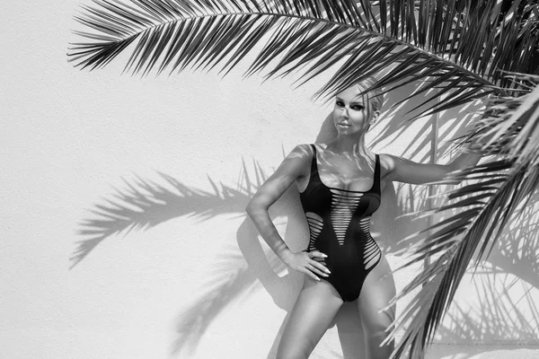 Vackra fenomenal fantastisk elegant sexig blond modell kvinna med perfekta ansikte bär en solglasögon står med eleganta erotiska baddräkt på fantastisk utsikt med palm tree skugga i Cannes, Frankrike — Stockfoto