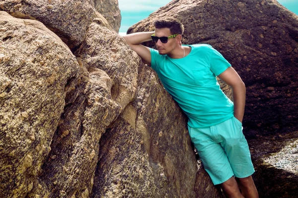 Елегантний красивий чоловік, одягнений у літній одяг, стоїть на скелях біля моря — стокове фото