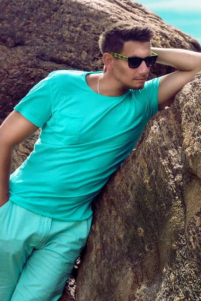 Елегантний красивий чоловік, одягнений у літній одяг, стоїть на скелях біля моря — стокове фото