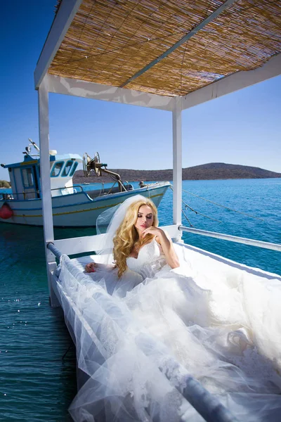 Vackra brud blond kvinnlig modell i fantastiska brudklänning ställer på ön Santorini i Grekland och bortom det är en vacker utsikt — Stockfoto