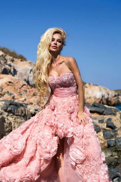 素晴らしいウェディング ドレスの美しい花嫁金髪女性モデルは、ギリシャのサントリーニ島にポーズし、向こうには美しい景色を — ストック写真