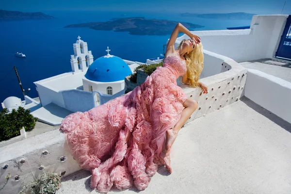 Beautiful bride blonde female model in amazing wedding dress poses on the island of Santorini in Greece and beyond it is a beautiful view — Stock Photo, Image