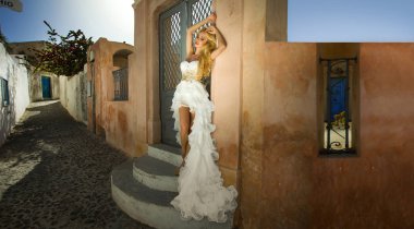 Santorini Adası Yunanistan üzerinde şaşırtıcı gelinlikle güzel gelin sarışın kadın model teşkil etmektedir ve ötesinde bu kadar güzel bir manzara