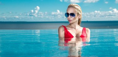 Islak saç ve zarif makyaj takı, kristal ve ıslak çıplak vücut ile küpeler harika manzaralı lüks otel, bir havuzda oturan güzel sarışın kadın model