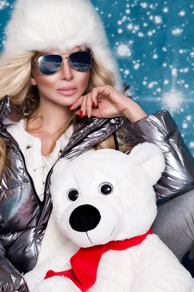 Piękne wspaniałe kobiety, z długimi blond włosami i idealną twarz ubrany w odzież zimowa, srebrny ciepłe Kurtki i futra WPR i srebrne okulary na tle zima — Zdjęcie stockowe