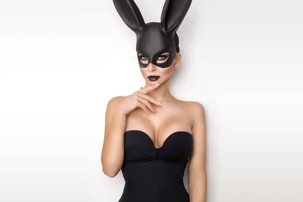 Sexy žena s velkými prsy nosí černou masku Velikonoční zajíček stojící na bílém pozadí a vypadá velmi smyslně — Stock fotografie