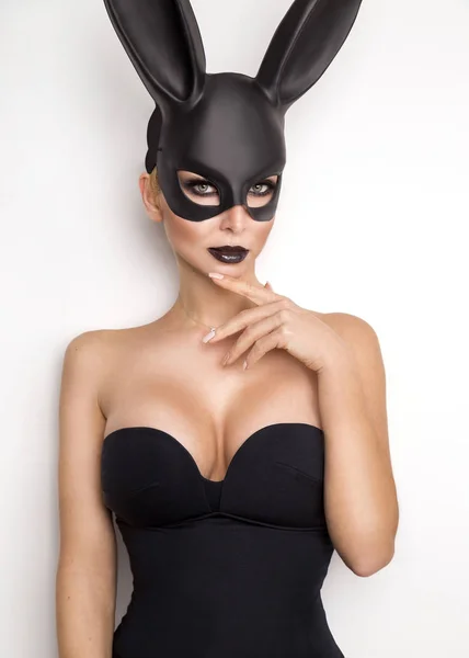 Sexy vrouw met grote borsten, het dragen van een zwart masker paashaas staande op een witte achtergrond en ziet er zeer sensueel — Stockfoto