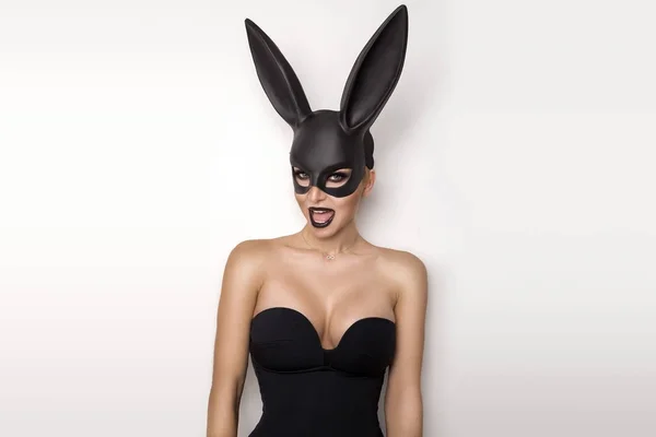 Sexy vrouw met grote borsten, het dragen van een zwart masker paashaas staande op een witte achtergrond en ziet er zeer sensueel — Stockfoto