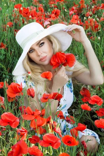 Loira bonita com cabelos longos e lábios de beleza, de pé em um prado de papoilas vermelhas — Fotografia de Stock