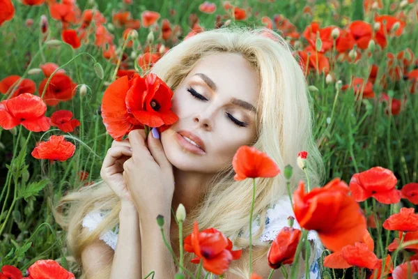 Uzun saç ve güzellik dudaklı, kırmızı haşhaş bir çayır üzerinde duran güzel sarışın