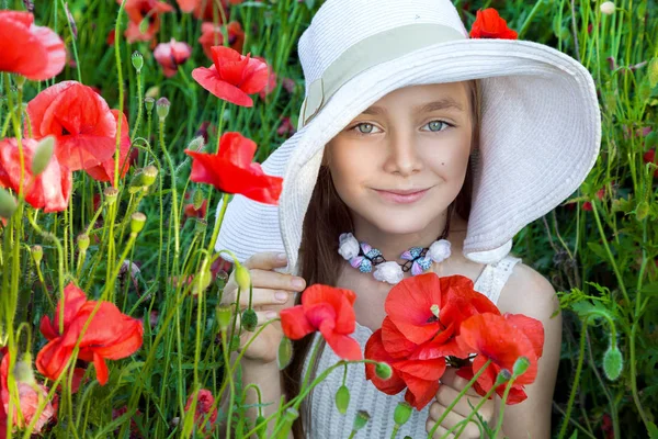 Menina doce em um chapéu, de pé em um prado e segurando papoulas vermelhas — Fotografia de Stock