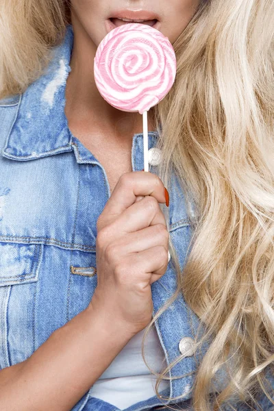 Porträtt av sexig blond kvinnlig modell klädd i jeans, lollipops slicka — Stockfoto