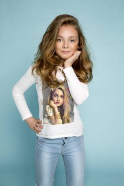 Güzel sevimli küçük sarışın kız kot jeans mavi bir arka plan üzerinde