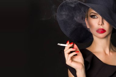 Zarif kadın, femme fatale siyah şapka ile sigara elinde. Siyah arka plan üzerine